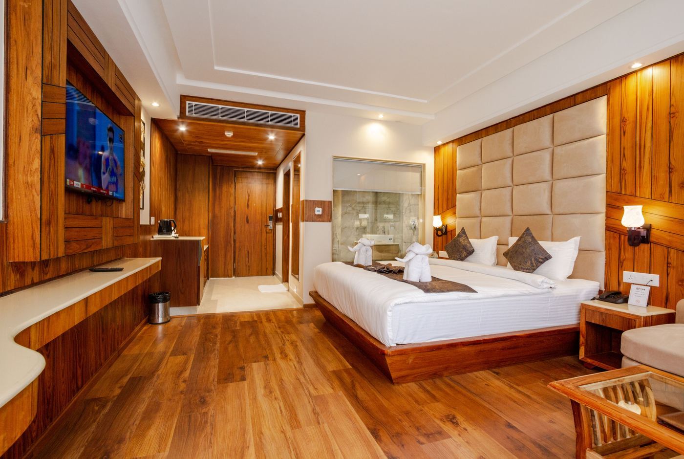 Habitación de hotel con piso de madera y cabecera tapizada — diseño interiorismo hotelero