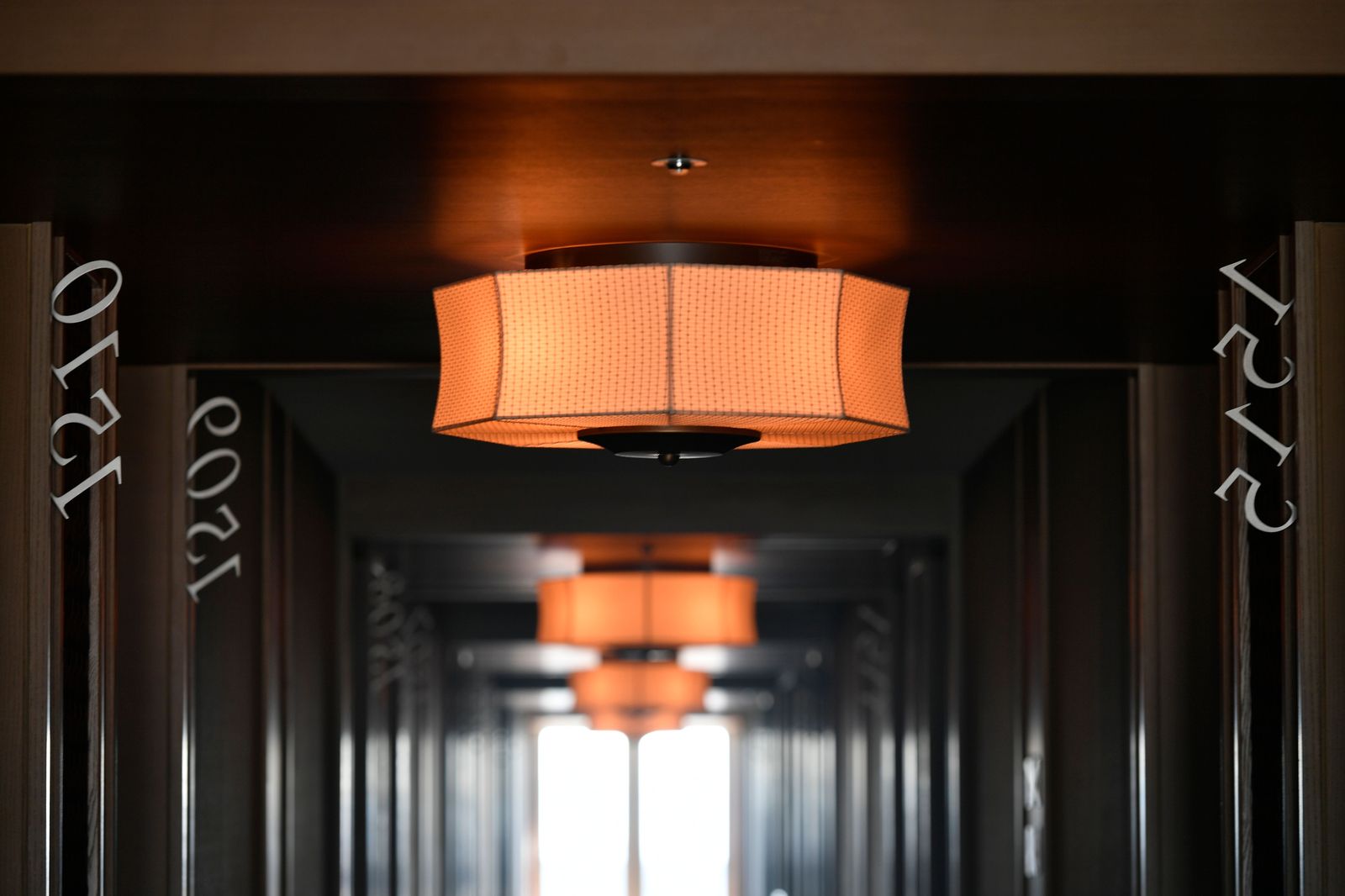 Pasillo de hotel con lámparas de diseño y numeración de habitaciones — control de calidad en instalación de OS&E